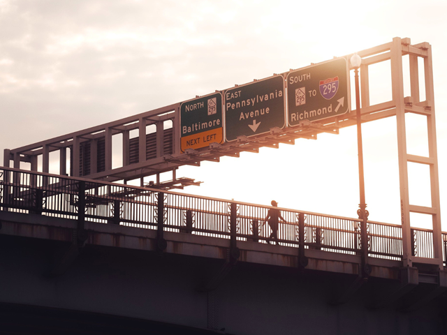 Woman walking on East Pennsylvania Avenue with interstate signs over head in Washington DC